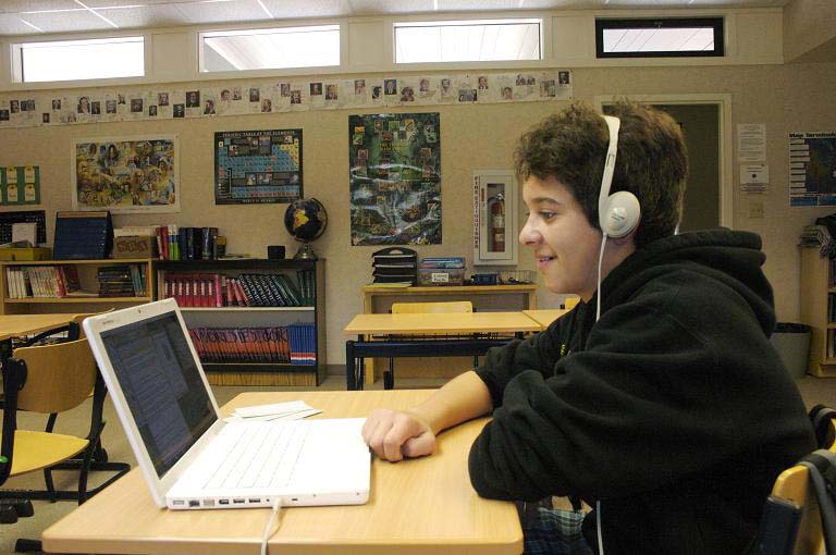 Male student with headphones enjoying an audiobook.